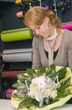 Female florist working in a flower store, making the bouquet ready for the customer
