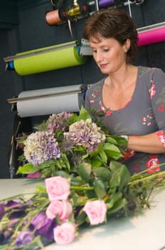 Female florist working in a flower store, making the bouquet ready for the customer