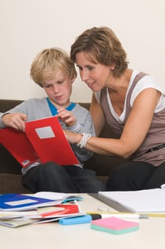 Boy is doing his homework in the livingroom while mother is helping him