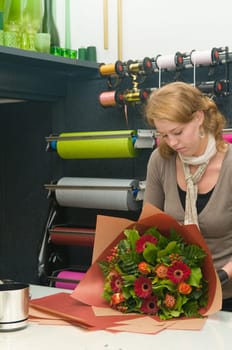 Female florist working in a flower store, making the bouquet ready for the customer