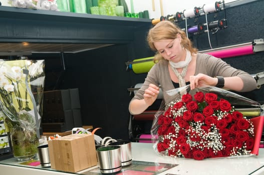 Female florist working in a flower store, making the bouquet ready for the customer