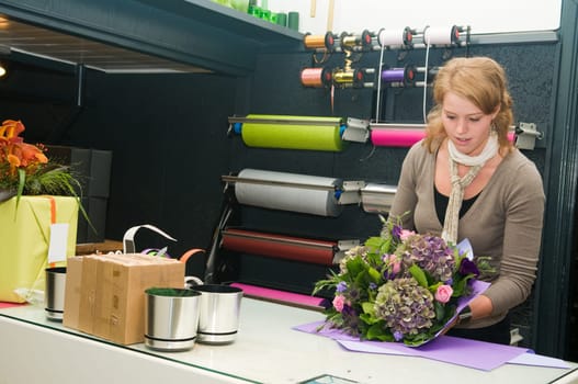 Female florist working in a flower store, making the bouquet ready for the customer