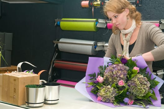 Female florist working in a flower store, making the bouquet ready for the customer