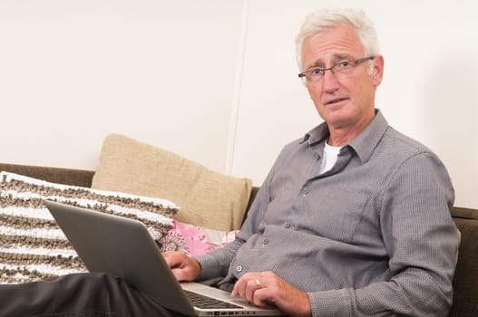 Senior working on a laptop while sitting on the couch
