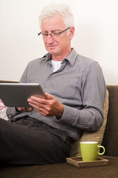 Senior working on a tablet pc while sitting on the couch