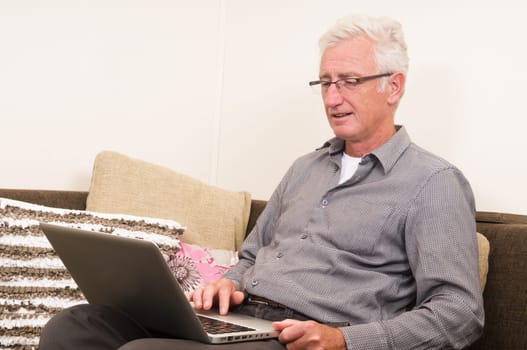 Senior working on a laptop while sitting on the couch