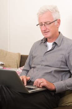 Senior working on a laptop while sitting on the couch