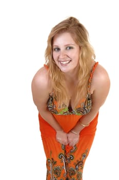 A lovely teenage girl with blond hair and a colorful orange long dress standing and bending down to the camera, over white background.
