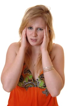 A pretty teenager girl with heavy headache holding her hands on her head to release her pain, in a colorful orange dress over white background.