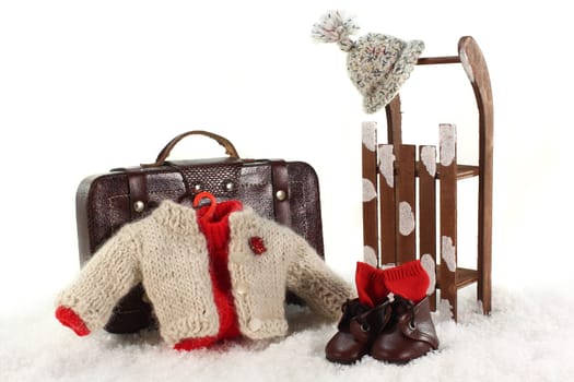 Sleigh,suitcase and winter clothes against white background