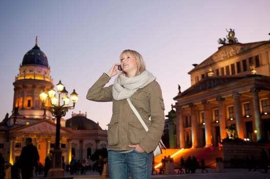 Young woman talking on the phone in the city in the evening