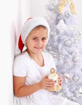 Girl holding bell with Christmas tree in background