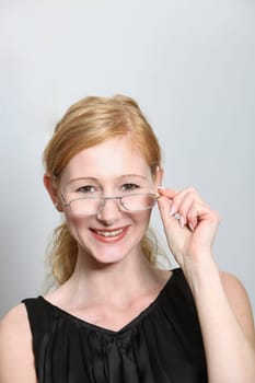 Young woman laughing looking over the rim of glasses - vertically