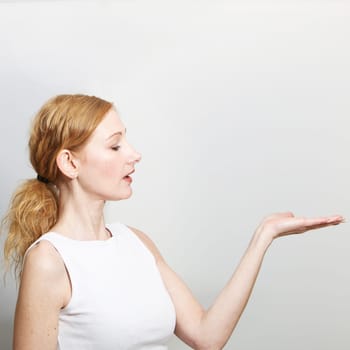 Woman presents something on her hand - with copy space. She looks at her hand.- Square
