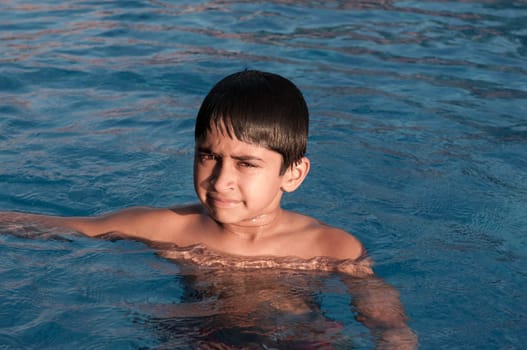 an handsome indian boy swimming happily in the pool