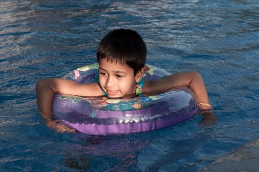 an handsome indian boy swimming happily in the pool