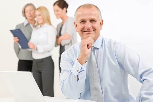 Business team happy mature businessman with attractive colleagues looking file