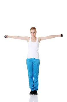 Teen pretty standing caucasian girl holding dumbbells doing exercise.