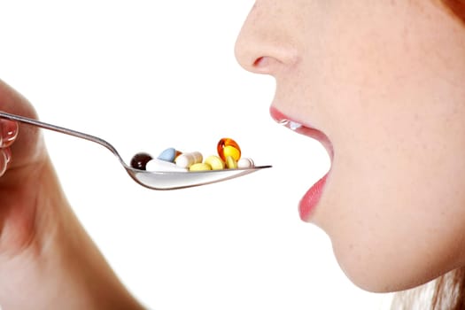 Closeup on teen caucasian girl`s open mouth taking pills from spoon.