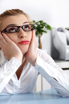 Beautiful caucasian woman in glasses holding head in her hands and looking up.