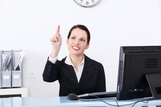 Pretty caucasian smiling businesswoman pushing an abstract button in the office.