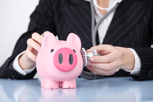 Closeup on examining pink piggy bank by caucasian businesswoman.