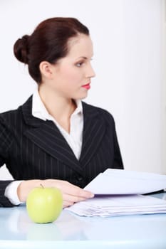 Green apple lying on the desk in the businesswoman`s office.