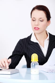 Pretty caucasian businesswoman sitting near baby bottle.