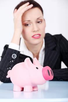Pretty caucasian businesswoman looking at her piggy bank.