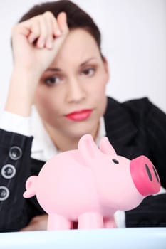 Pretty caucasian businesswoman looking at her piggy bank.