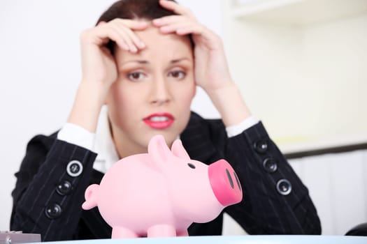 Pretty caucasian businesswoman in depression with piggy bank.