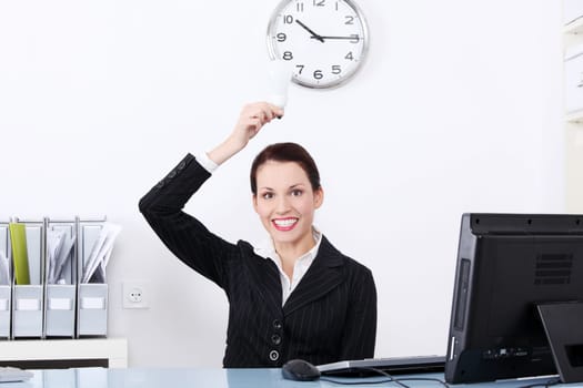 Pretty caucasian businesswoman holding a light bulb in the office.