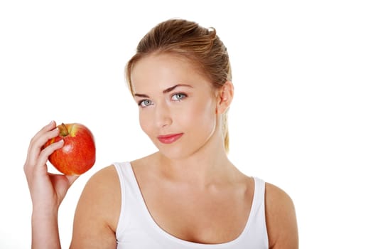 Young beautiful woman eating red apple looking towards camera
