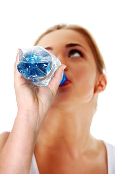 Close up of teen woman drinking mineral water from bottle. Focused on bottle