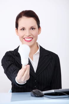 Pretty caucasian businesswoman holding a light bulb in the office.