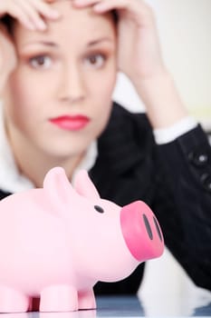 Pretty caucasian businesswoman in depression with piggy bank.
