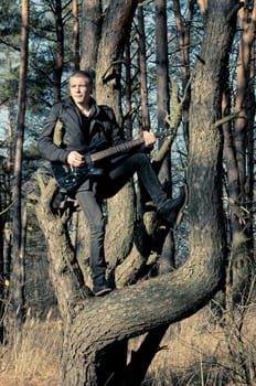 teen musician plays the guitar in the autumn forest