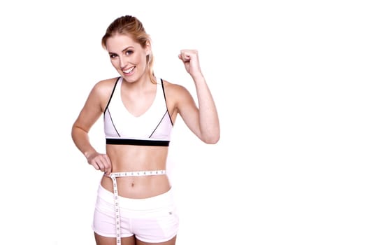 Woman taking a measurement around her waist and she is happy with the result.