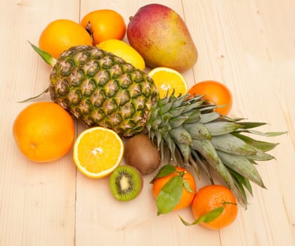 Tropical Fruits - Pineapple, Oranges, Persimmon, Kiwi, Mango and Tangerines on Wooden Background
