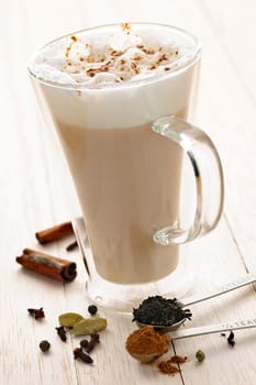 Chai latte spiced tea beverage in glass mug with spices