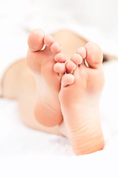 Soles of soft female bare feet crossed in closeup