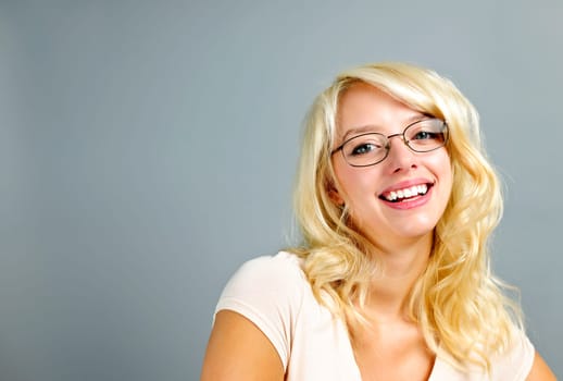 Smiling young woman wearing eyeglasses on grey background