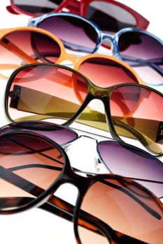 Assorted styles of tinted sunglasses on white background close up
