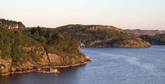 Rocky sea coast in sunset - Norwegian fjords  clear sky, still water with ripples