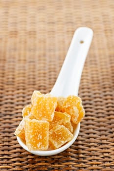 Caramelized ginger candy pieces on white spoon