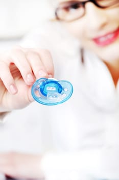 Young businesswoman in glasses giving a dummy to her child in the office.