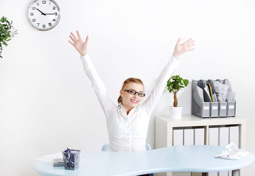 Young caucasian woman sitting in the office with her hands in the air.
