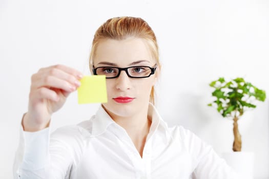 Young caucasian bussineswoman looking at yellow sheet of paper in the office.