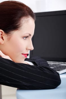 Pretty caucasian thinking businesswoman lying on the desk in the office.
