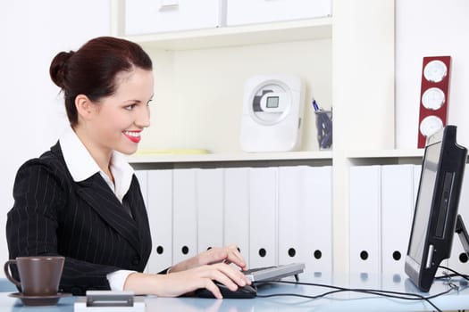Beautiful caucasian smiling businesswoman sitting by computer in the office.